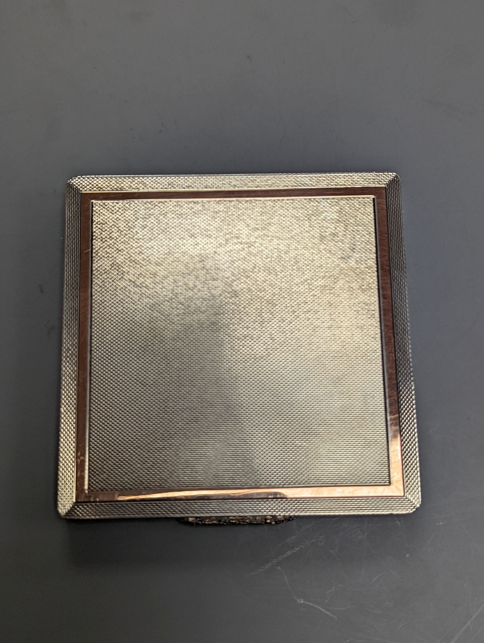 A 1960's Garrard & Co yellow metal mounted engine turned silver cigarette case, Birmingham, 1965, 88mm.